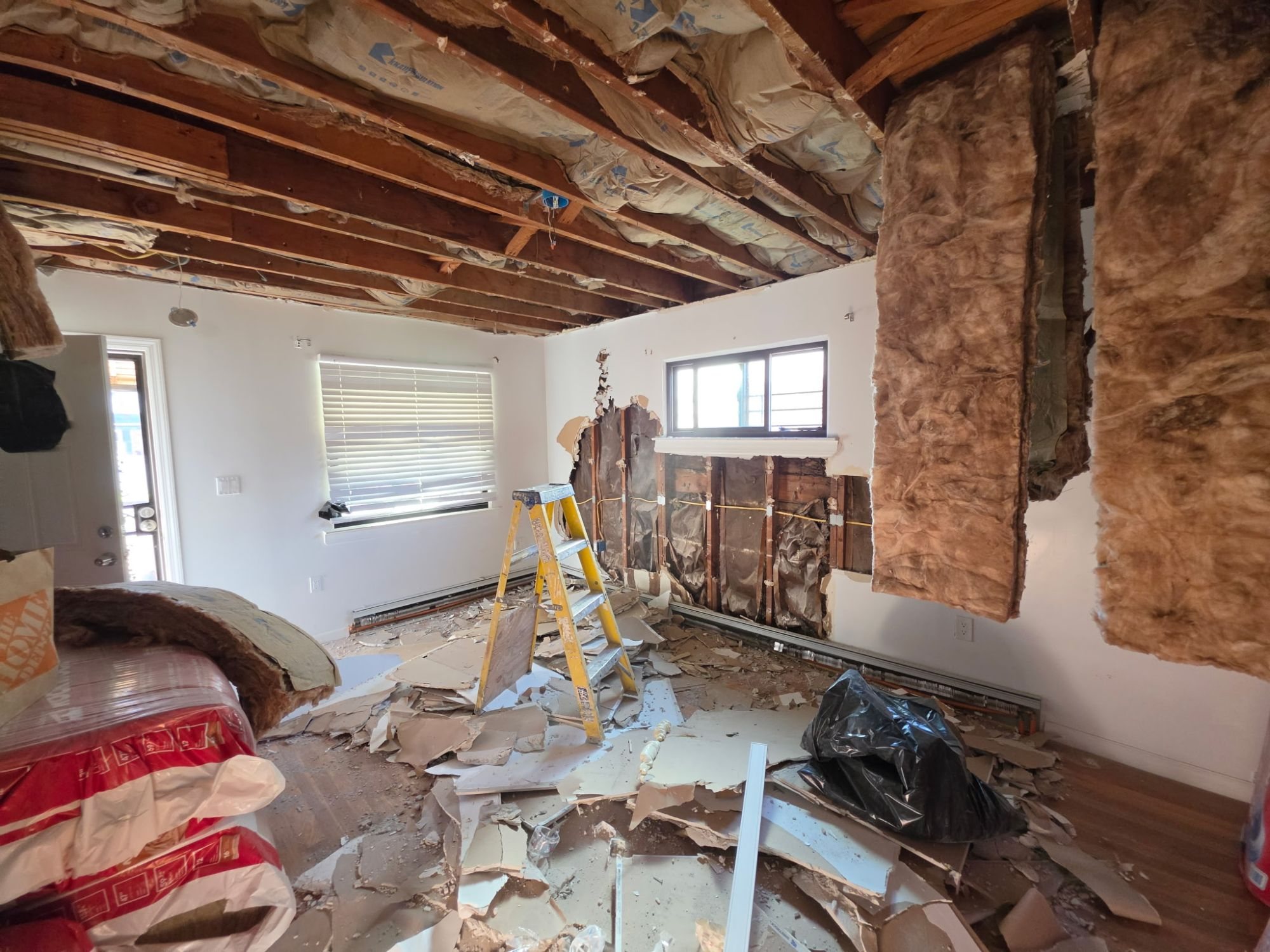 Living room during demolition with the ceiling opened to the joists and walls opened to the studs