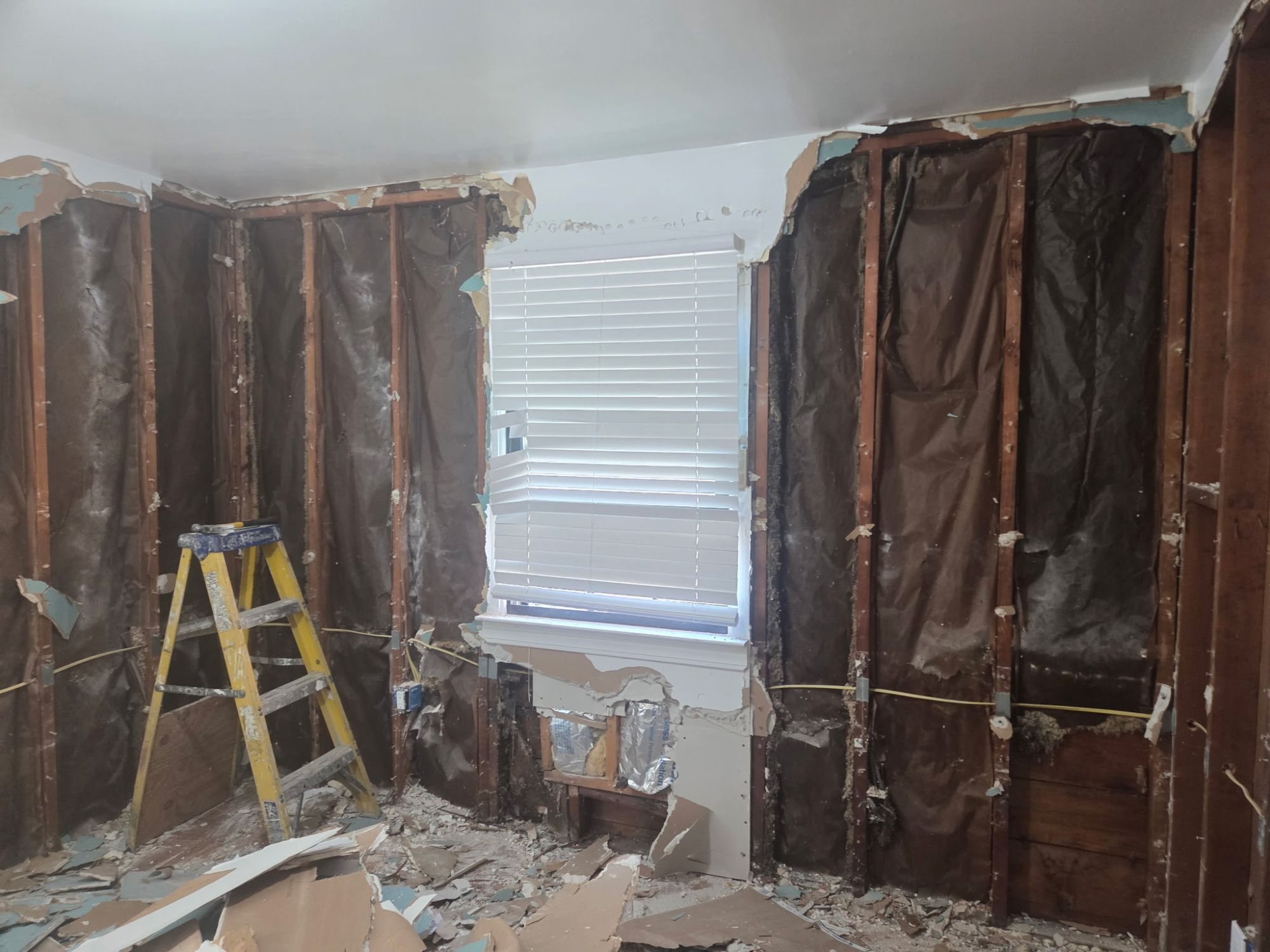 Wall opened to the studs around a window during demolition